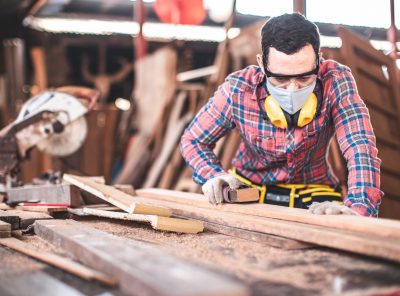 Carpenter working on woodworking machines in carpentry shop. Carpenter marks out the details of the furniture .