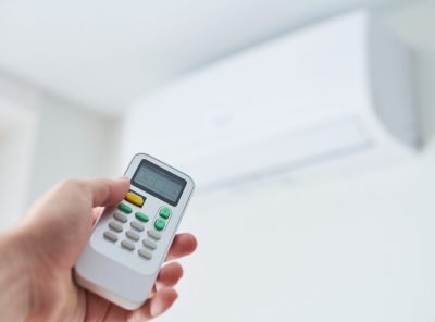 Remote control for air conditioner in hand. Room condition remote control. Air temperature switch for cooling of space.