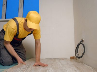 Skilled master laying laminate floor in apartment. Construction worker is engaged in laying laminate in the room. Repair and finishing work.